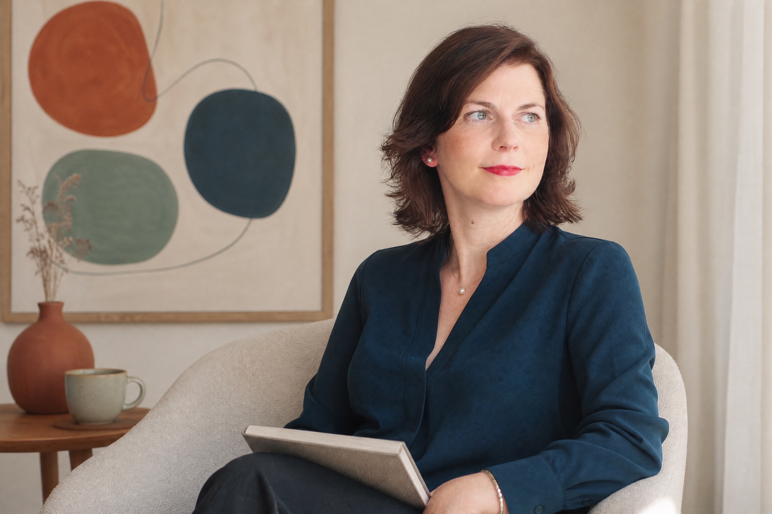 KI-Bild nach echtem Foto: Linda Groß nachdenklich, den Blick zum Fensterlicht gewandt, mit Notizbuch in der Hand.